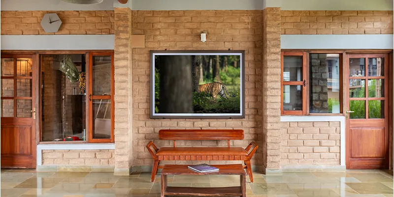 Reception entrance with wooden bench and brick architecture at Waghoba Eco Lodge